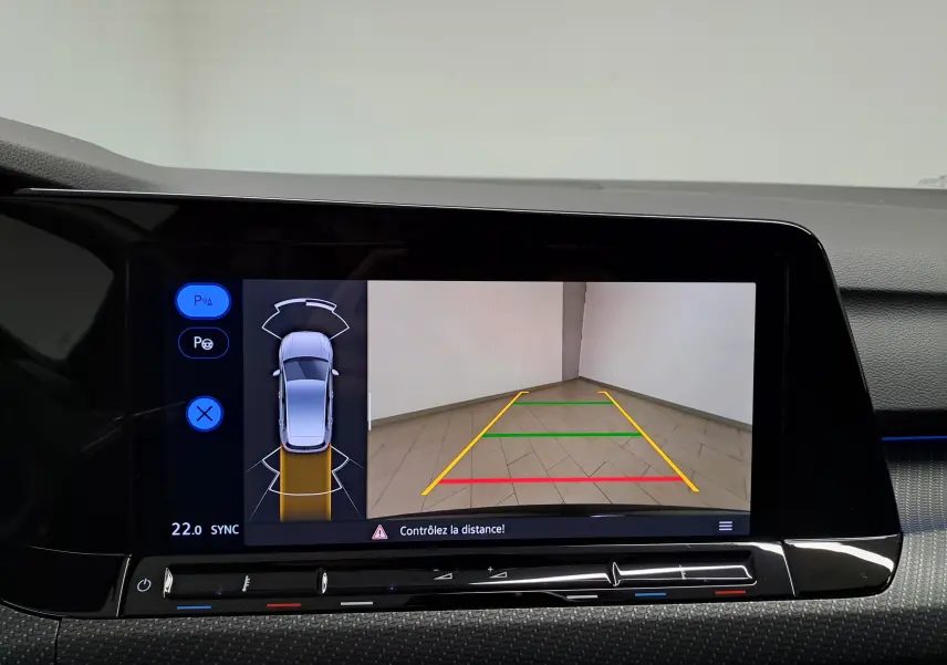 Écran de caméra de recul et assistance au stationnement dans une Volkswagen Golf noire intense nacrée, vue intérieure.