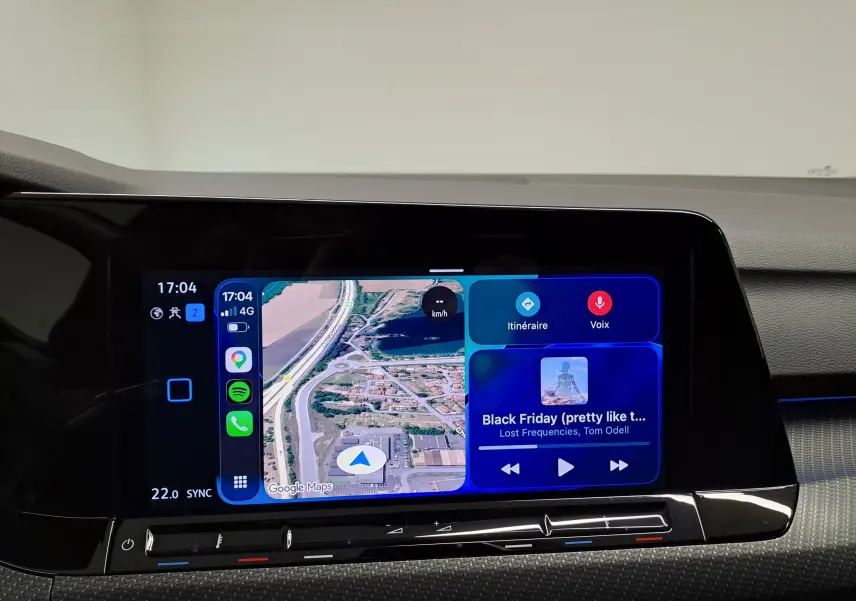 Écran tactile central de la Volkswagen Golf 1.5 eTSI 2023 affichant la navigation Google Maps et la musique en cours.
