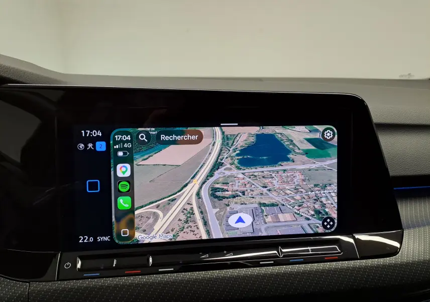 Écran tactile central affichant la navigation Google Maps dans l'habitacle d'une Volkswagen Golf noire.