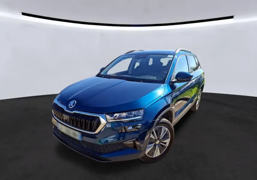 Vue 3/4 avant droite d'un Skoda Karoq bleu métallisé avec calandre chromée et jantes alu 17 pouces.