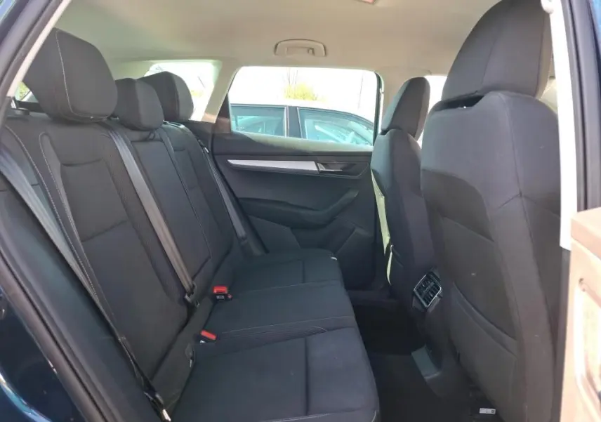 Vue intérieure arrière côté gauche du Skoda Karoq bleu 2026, montrant les sièges arrière noirs et les aérateurs centraux.