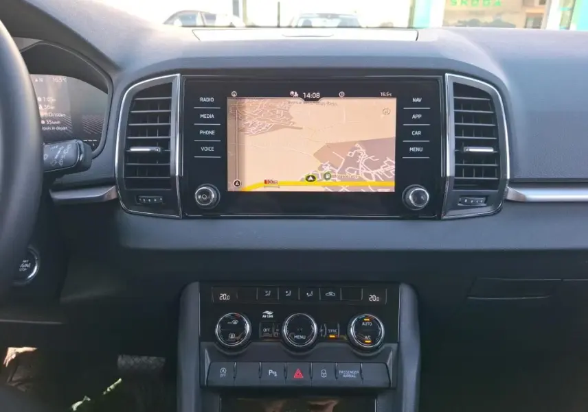 Vue intérieure centrée sur la console centrale du Skoda Karoq avec écran tactile de navigation et commandes de climatisation.