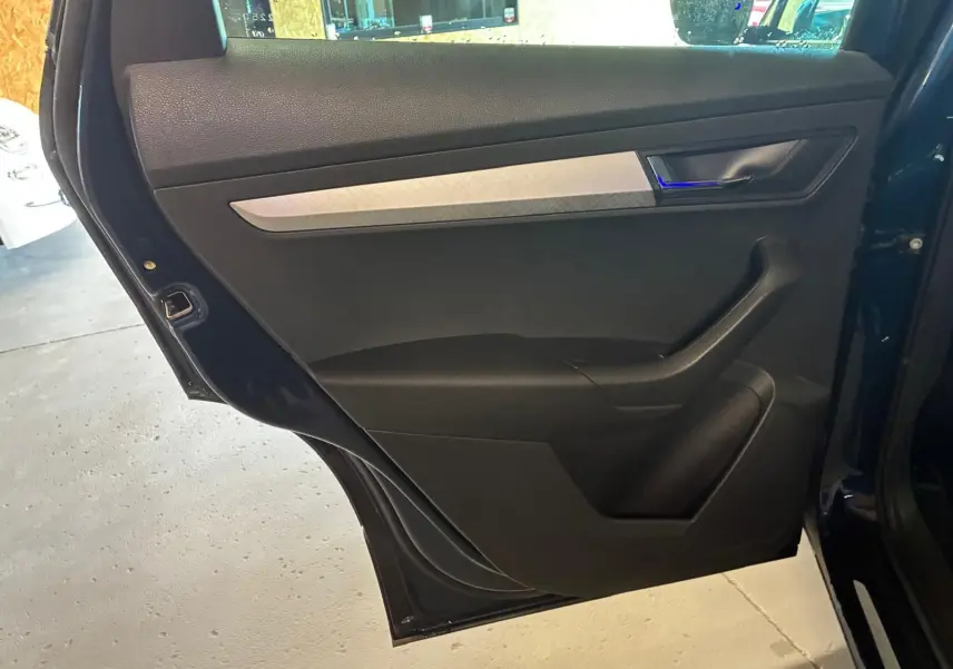 Vue rapprochée de la porte arrière gauche noire du Skoda Karoq bleu 2023 avec poignée intégrée et insert décoratif gris.