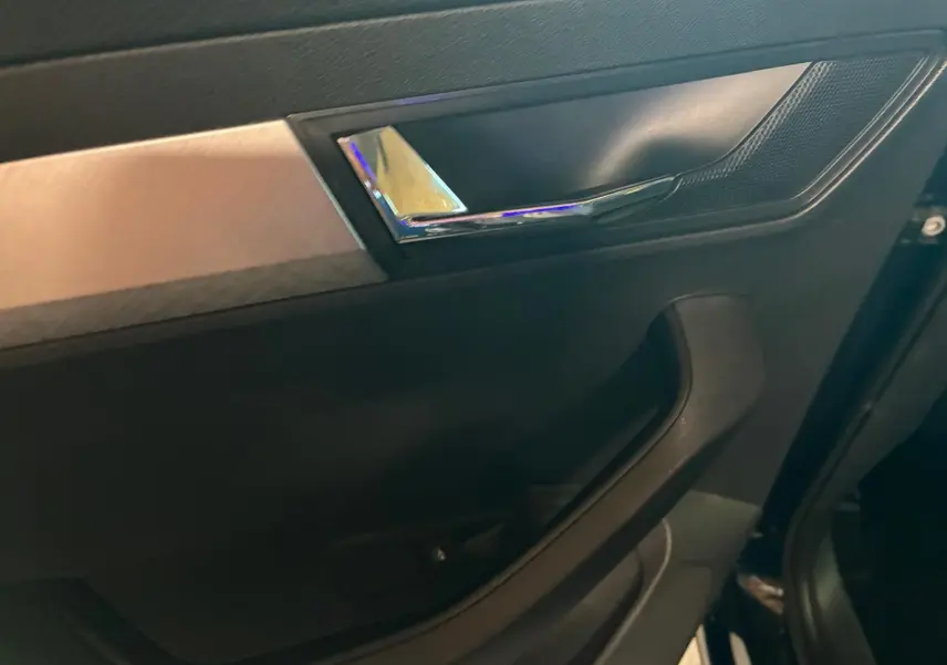 Détail de la porte intérieure côté gauche du Skoda Karoq 2023 avec poignée chromée et insert décoratif gris.