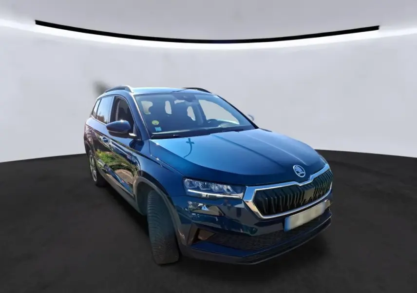 Vue 3/4 avant gauche d'un Skoda Karoq bleu métallisé avec calandre chromée et jantes alu 17 pouces sur fond neutre.