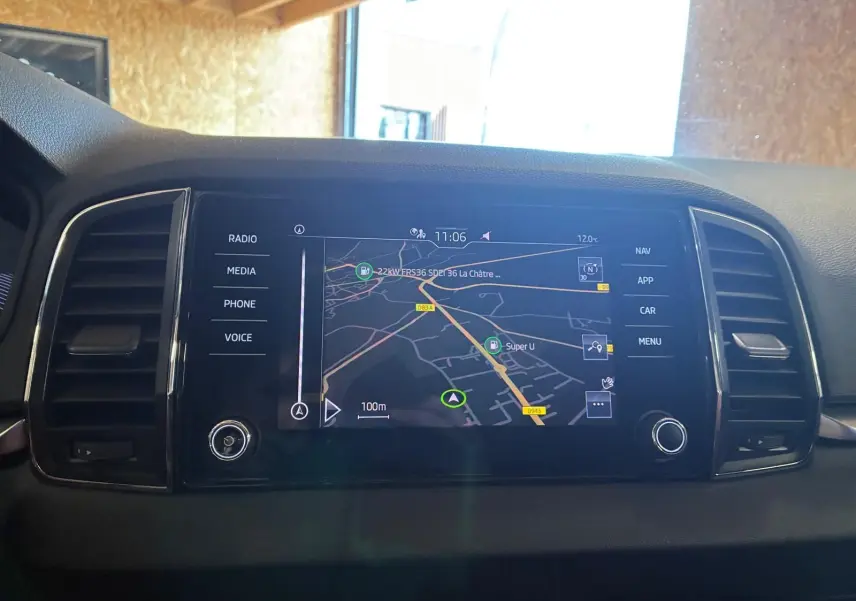 Écran tactile central avec navigation affichée, entouré d'aérateurs noirs dans l'habitacle d'un Skoda Karoq bleu.