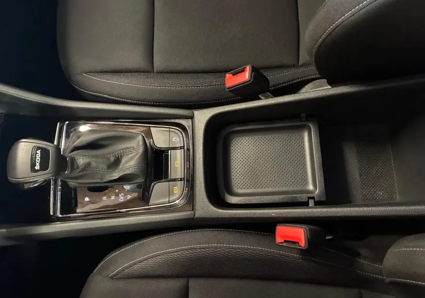 Vue plongeante sur la console centrale noire avec levier de vitesse automatique et sièges tissu noir du Skoda Karoq bleu 2023.