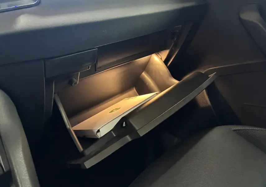 Intérieur de la Skoda Karoq 2023, boîte à gants ouverte avec éclairage intérieur et document visible.