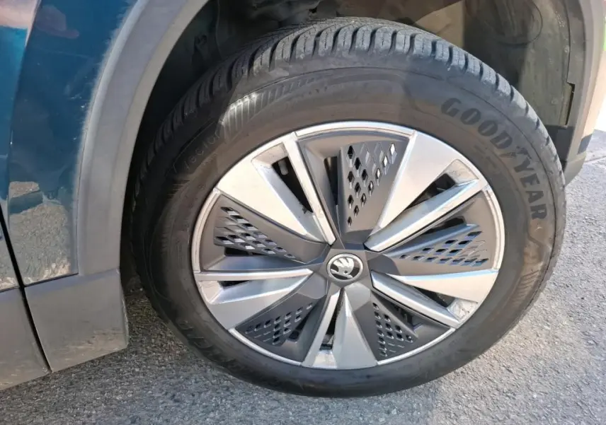 Gros plan sur la roue avant droite d'un Skoda Karoq bleu, jante alu 17 pouces avec logo central chromé.