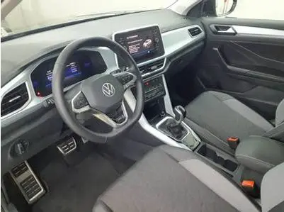 Intérieur du Volkswagen T-Roc 2025 vu côté conducteur, tableau de bord numérique et volant multifonction gris foncé.