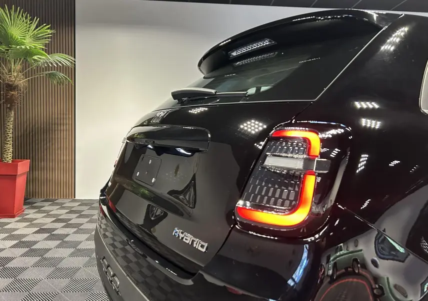 Vue 3/4 arrière droite d'une Fiat 600 noire hybride avec feux arrière LED et logo Hybrid sur hayon.
