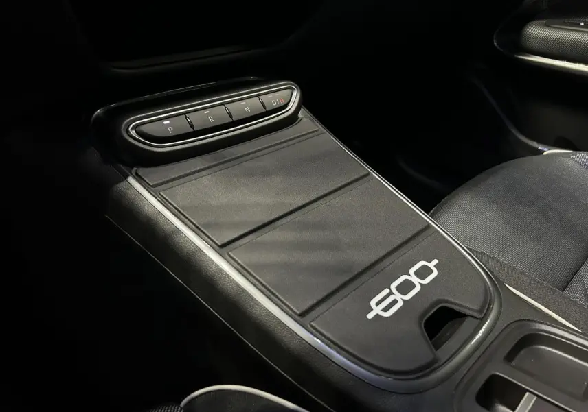 Gros plan sur la console centrale noire du Fiat 600 avec commandes de boîte auto et logo 600 blanc visible.