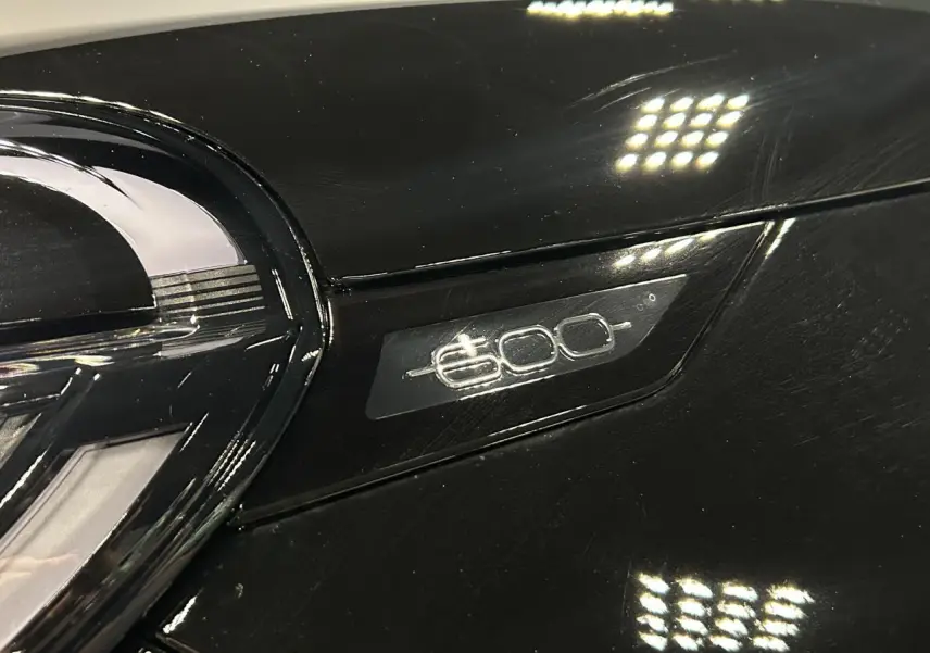 Gros plan sur le logo 600 argenté sur la calandre noire brillante d'une Fiat 600 hybride.