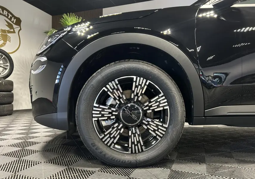 Gros plan sur la roue avant gauche noire du FIAT 600 hybride, avec jante alliage noire et détails argentés.