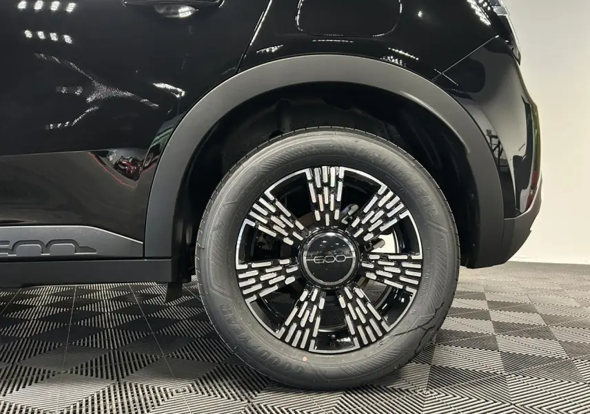 Gros plan sur la roue arrière droite noire de la Fiat 600 hybride avec jante alliage noire et détails argentés.