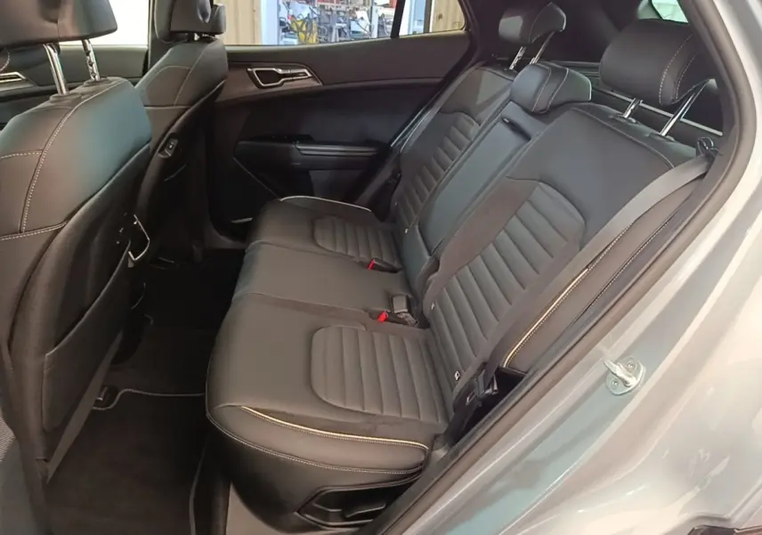Vue intérieure côté droit montrant la banquette arrière en cuir noir avec surpiqûres blanches du Kia Sportage gris clair 2022.
