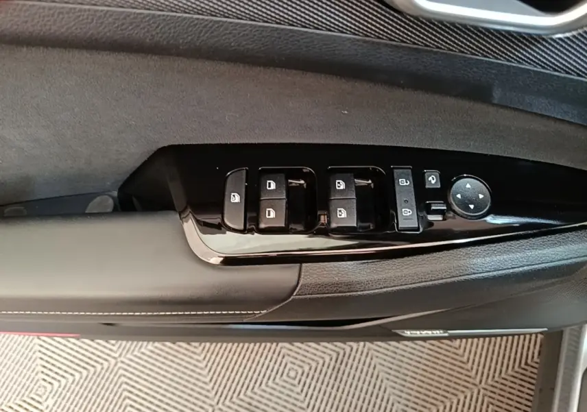 Gros plan sur la commande des vitres et rétroviseurs côté gauche d'une porte intérieure noire du Kia Sportage gris clair 2022.
