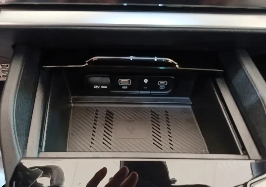 Gros plan sur la console centrale du Kia Sportage 2022, montrant les prises USB, 12V et recharge sans fil.