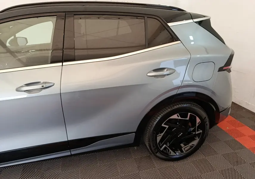 Vue côté droit arrière du Kia Sportage gris clair hybride rechargeable avec jantes noires au design moderne.