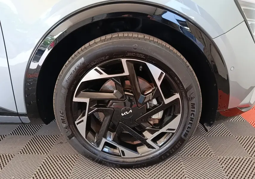 Gros plan sur la roue avant gauche grise du Kia Sportage 2022 avec jante noire et argent au design géométrique.