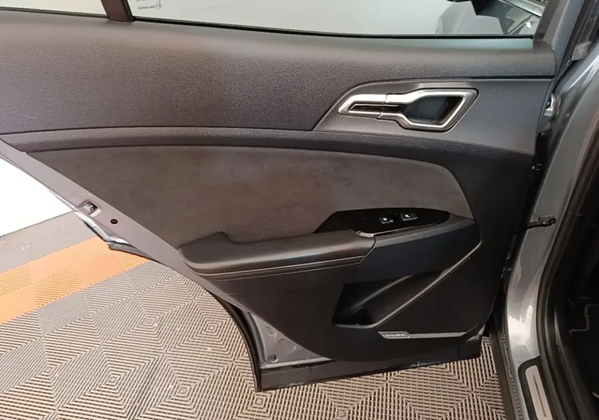 Vue intérieure de la porte arrière gauche gris clair du KIA Sportage 2022 avec garniture noire et commandes de fenêtre.
