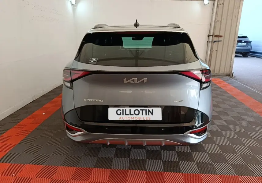 Vue arrière d'un KIA Sportage gris clair 2022 avec logo moderne et feux arrière en forme de flèche dans un garage.
