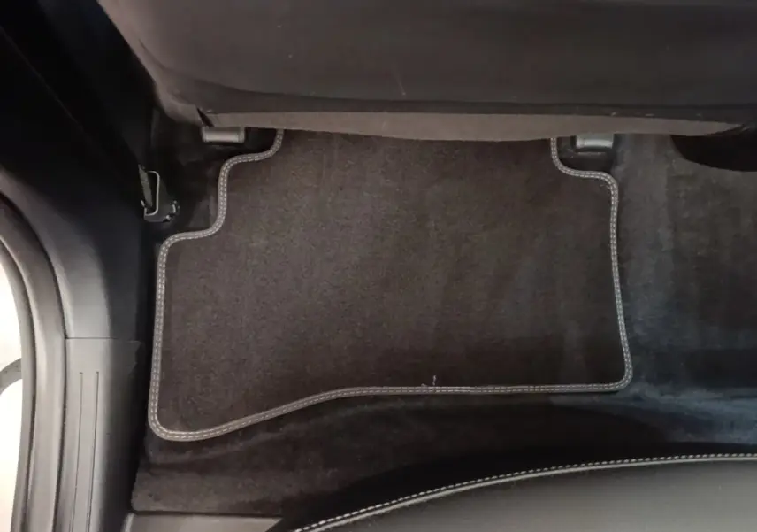 Détail du tapis de sol arrière noir avec surpiqûres blanches dans un KIA Sportage gris clair 2022.