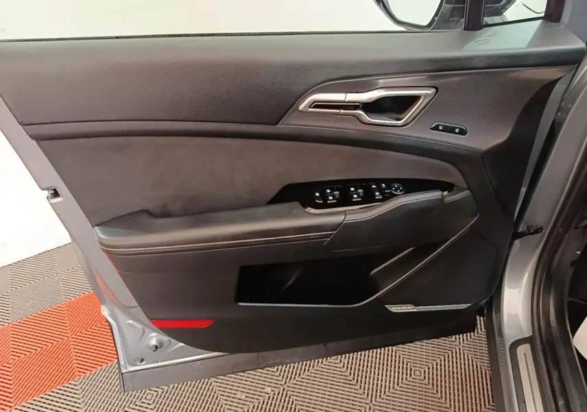 Vue intérieure de la porte avant gauche gris clair du Kia Sportage avec commandes électriques et garniture noire.
