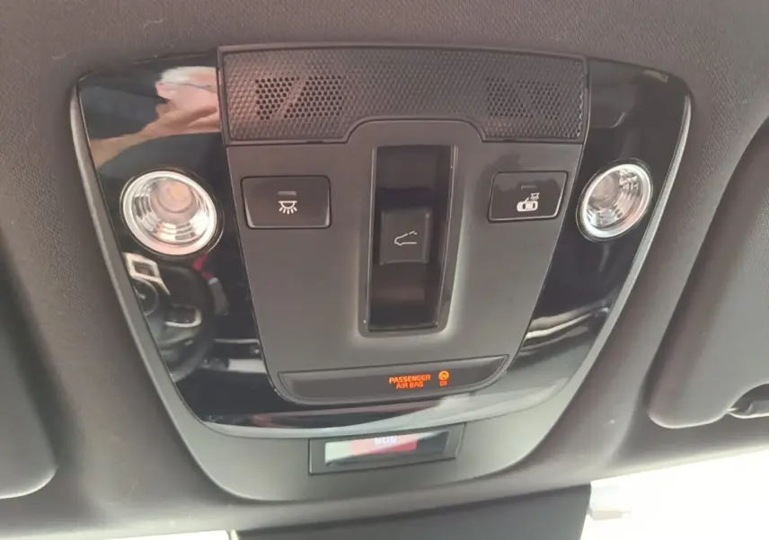 Vue intérieure du plafonnier noir brillant du Kia Sportage 2022 avec commandes d’éclairage et indicateur airbag passager.
