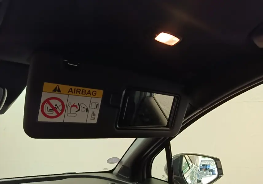 Intérieur du Kia Sportage 2022, vue côté passager avec pare-soleil ouvert et miroir intégré, éclairage intérieur allumé.