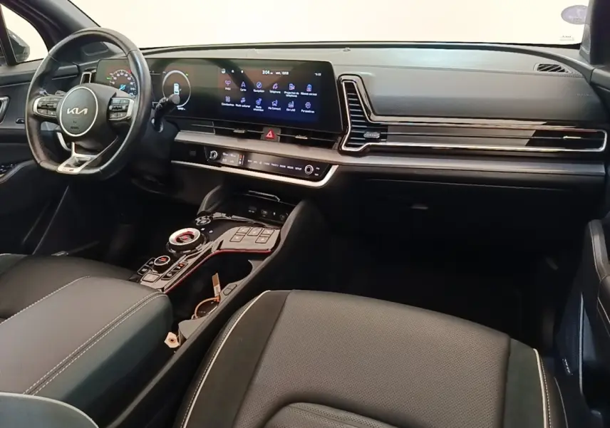 Intérieur du Kia Sportage 2022 vu côté conducteur, tableau de bord noir avec écran tactile large et volant multifonctions.
