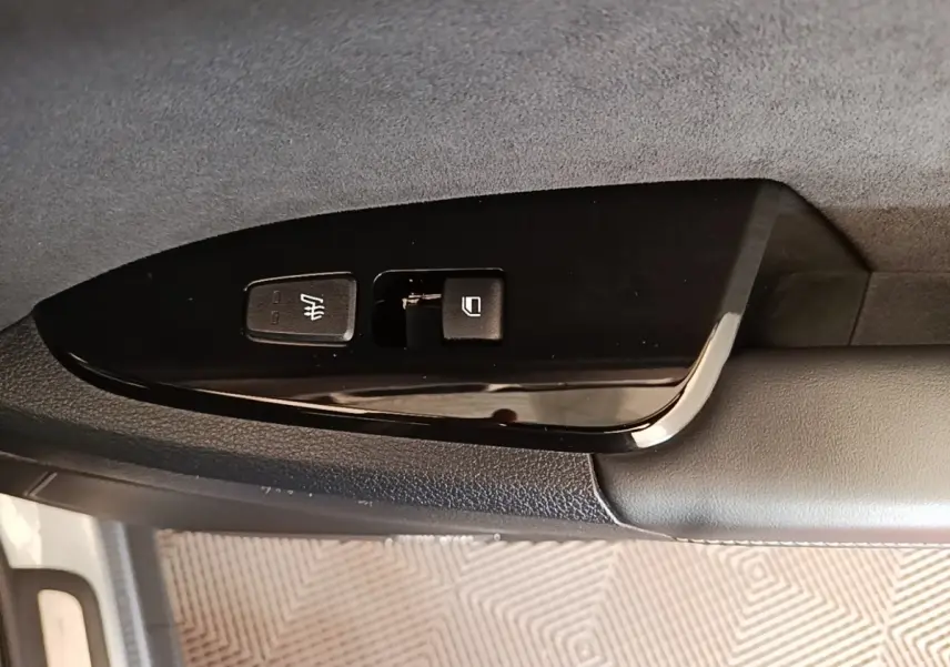 Détail des commandes de siège chauffant et verrouillage sur la porte côté conducteur d’un KIA Sportage gris clair.