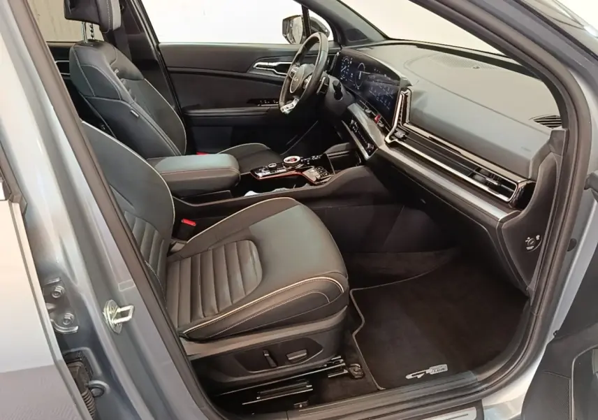Intérieur avant du Kia Sportage gris clair 2022, vue côté droit, sièges cuir noirs et tableau de bord digital large.
