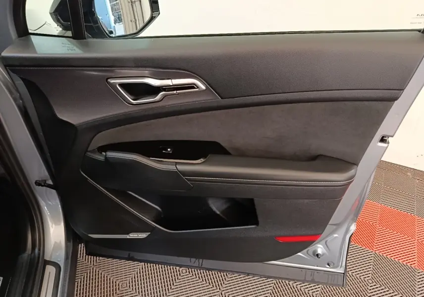 Vue intérieure côté gauche de la porte avant grise du Kia Sportage 2022 avec garniture noire et insert Harman Kardon.