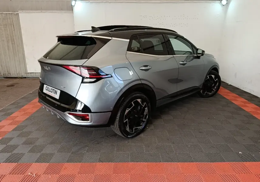 Vue 3/4 arrière droite du KIA Sportage gris clair hybride rechargeable avec toit noir et jantes noires stylisées.