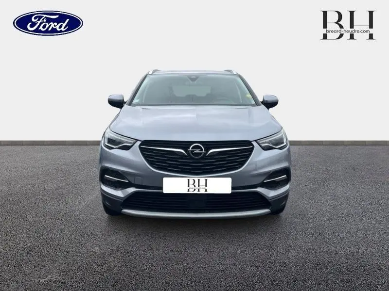 Vue avant d'un Opel Grandland X gris Quartz avec toit et rétroviseurs noirs, calandre et phares LED distinctifs.