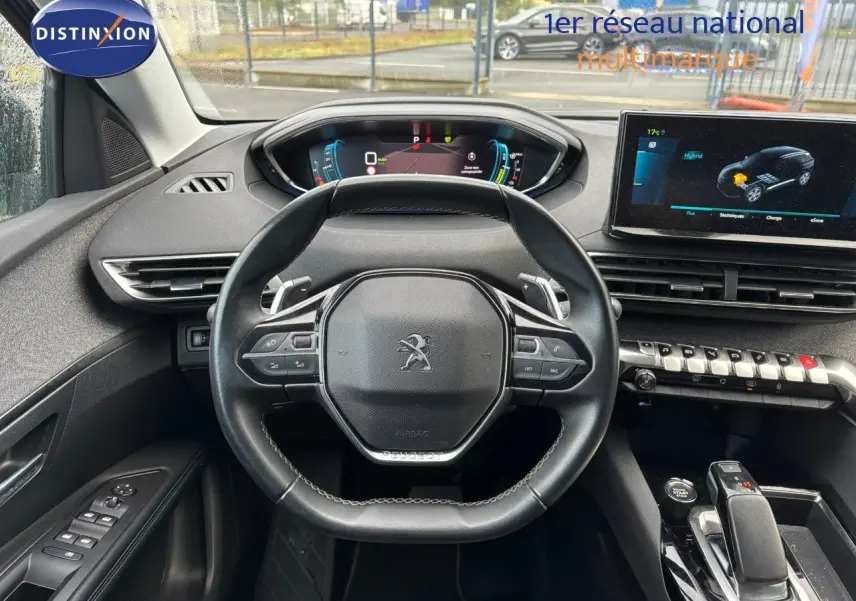 Vue intérieure centrée sur le volant noir du Peugeot 3008 hybride 2022 avec tableau de bord digital et écran tactile.