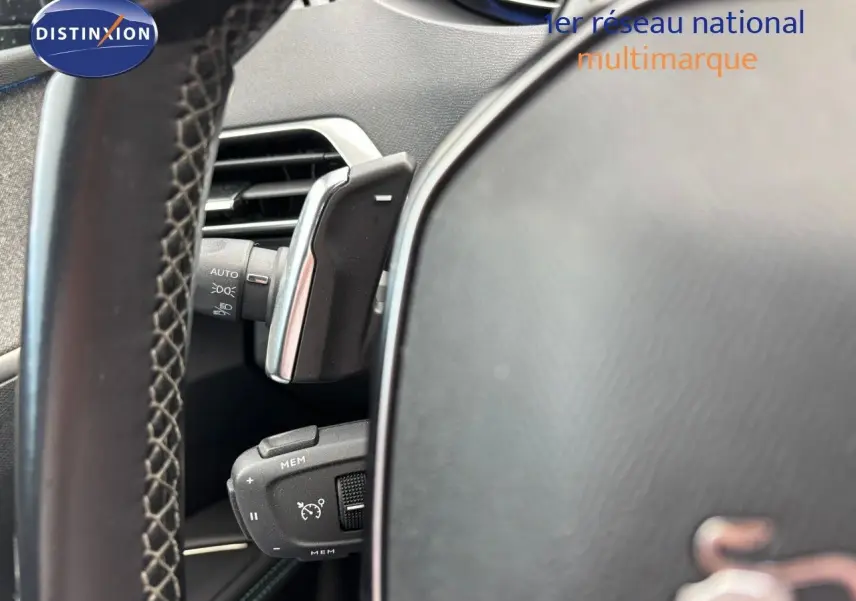 Gros plan sur le volant et les commandes à gauche du tableau de bord du Peugeot 3008 bleu Celebes Hybrid 2022.