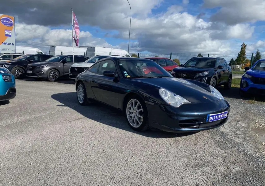 Porsche 911 Targa gris foncé vue en 3/4 avant droit sur un parking avec jantes sport et toit fermé.