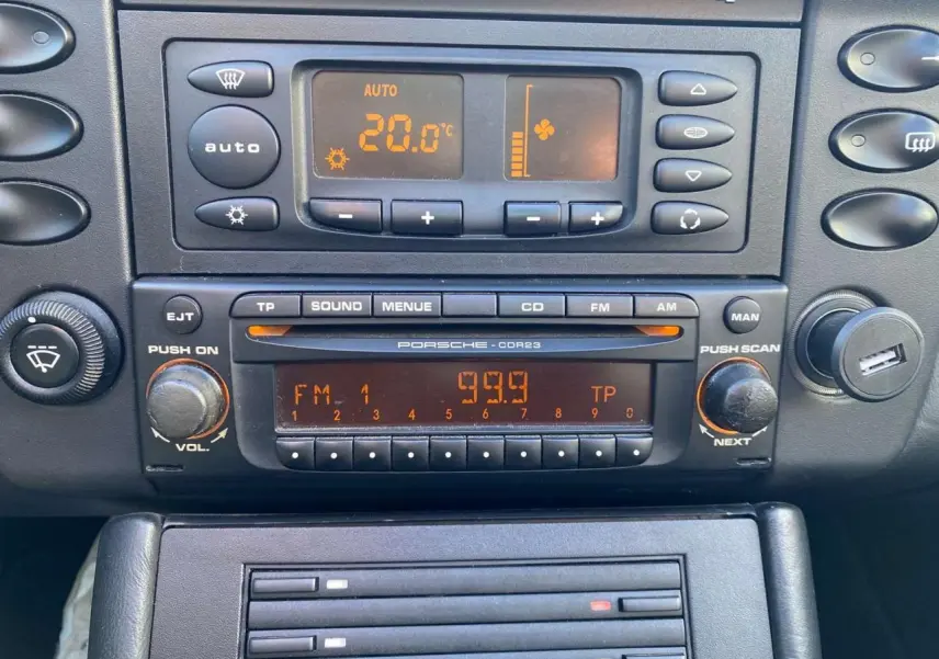 Détail de la console centrale de la Porsche 911 Targa 996 grise, affichant la climatisation et l’autoradio d’origine.