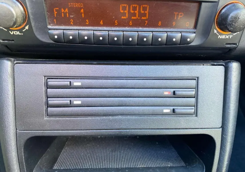 Gros plan sur la radio et le lecteur CD de la Porsche 911 Targa 996 gris foncé, intérieur cuir visible en arrière-plan.