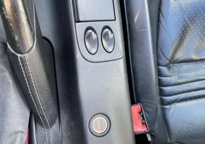 Gros plan sur la console centrale en cuir noir du Porsche 911 Targa 996 avec levier de frein à main et boutons de commande.