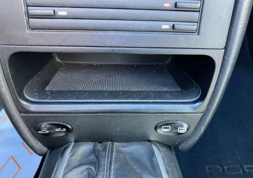 Gros plan sur la console centrale en cuir noir du Porsche 911 Targa 996, avec levier de vitesse et commandes d'ouverture des coffres.
