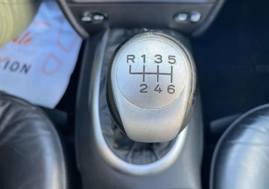 Gros plan sur le levier de vitesse manuel en alu et cuir de la Porsche 911 Targa gris foncé, intérieur cuir visible.