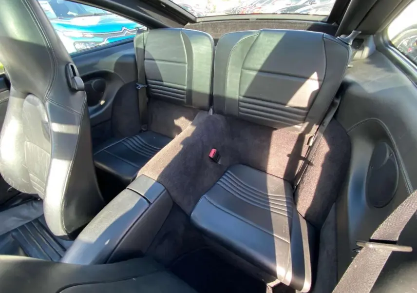Vue intérieure arrière montrant les sièges arrière en cuir noir du Porsche 911 Targa gris foncé de 2004.
