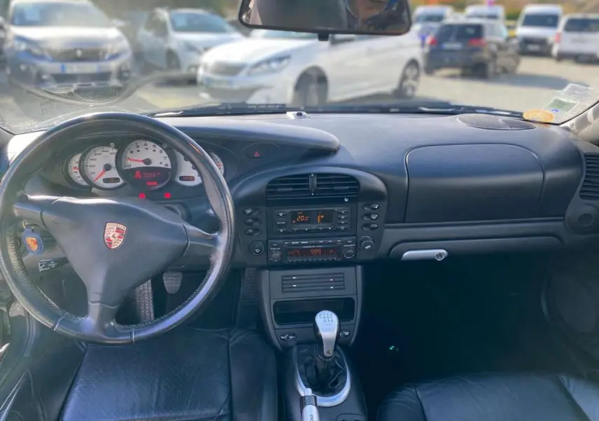 Vue intérieure avant de la Porsche 911 Targa gris foncé, avec volant cuir, tableau de bord et levier de vitesse alu-cuir.