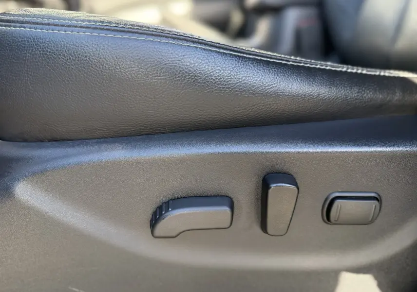 Gros plan sur les commandes de réglage électrique du siège cuir noir du Renault Alaskan brun 2018.