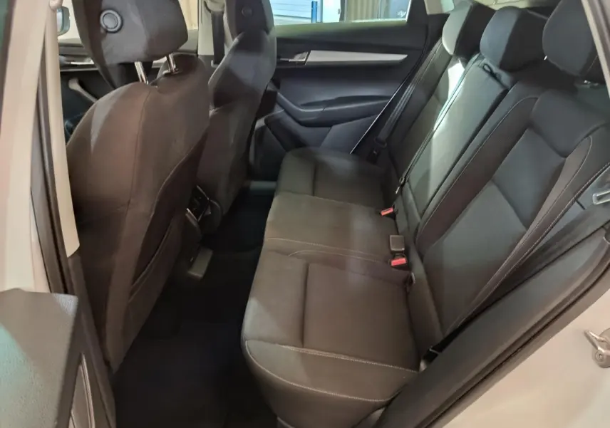 Vue intérieure côté droit montrant la banquette arrière noire du Skoda Karoq blanc 2024 avec ceintures et appuie-têtes.