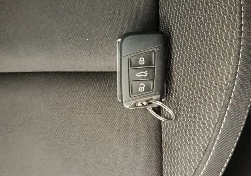 Clé de contact noire posée sur un siège tissu gris foncé à coutures blanches, intérieur d'un Skoda Karoq 2024.