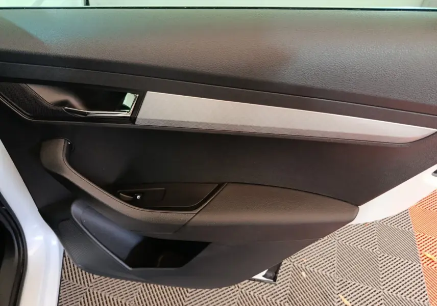 Vue intérieure côté gauche de la porte avant d’un Skoda Karoq blanc avec garniture noire et insert argenté.